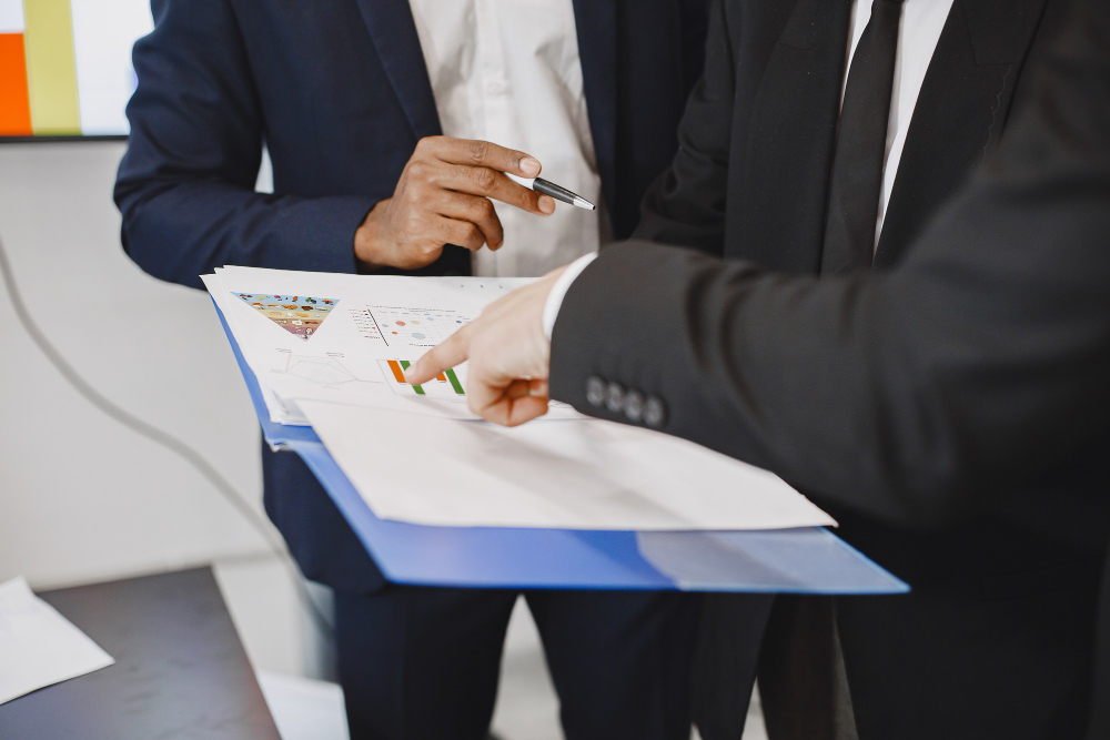 Two male managers discuss payroll services benefits at the office