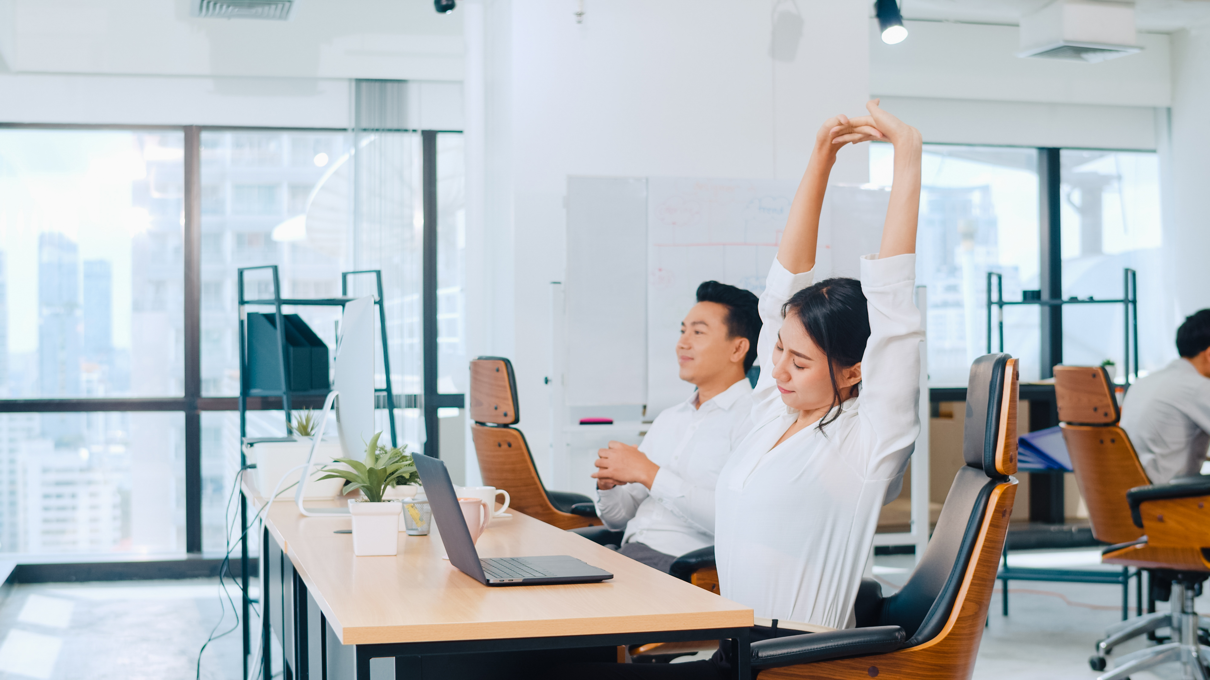 An office worker stretching at her desk, illustrating work-life balance - a common reasons for leaving a job.