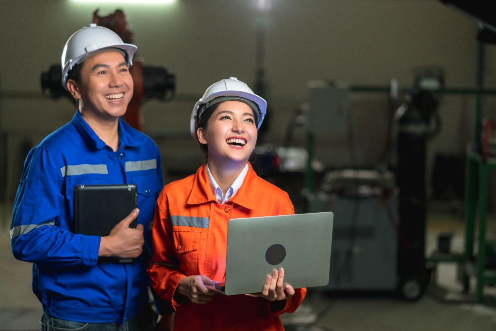 Two sales professionals in industrial trading discussing strategies, showcasing teamwork and advanced technology in a modern industrial setting.