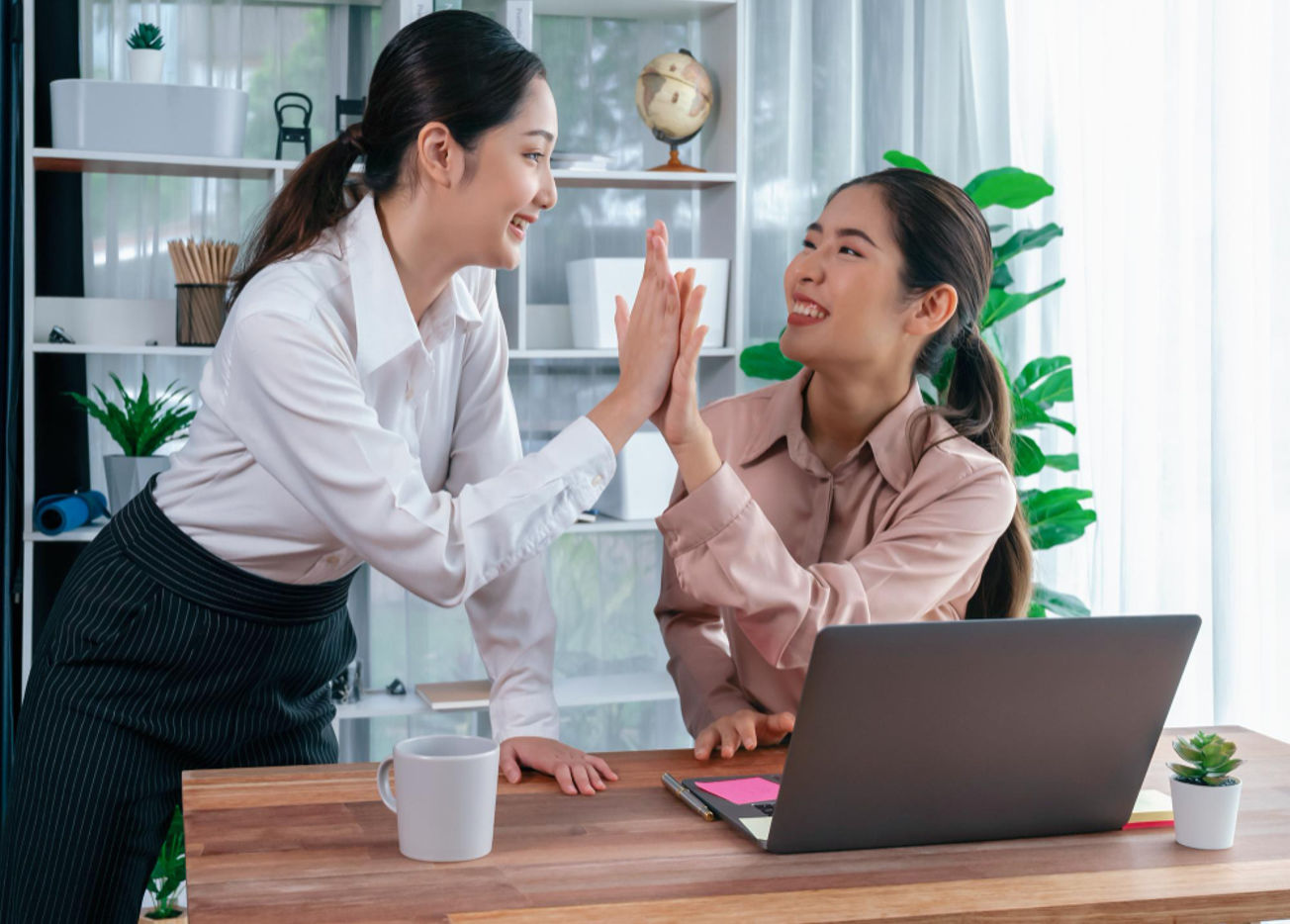 A female employee congrats her colleague on a successful achievement at work