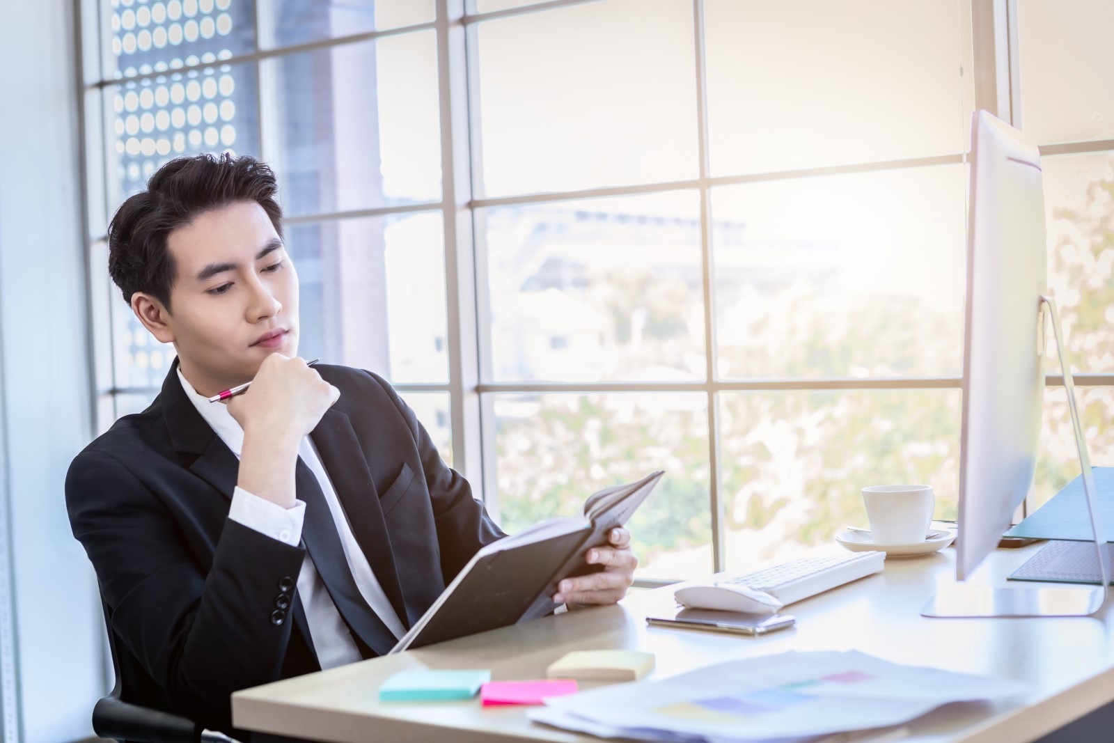 Office worker focusing on thinking with a notebook in hand at an office   