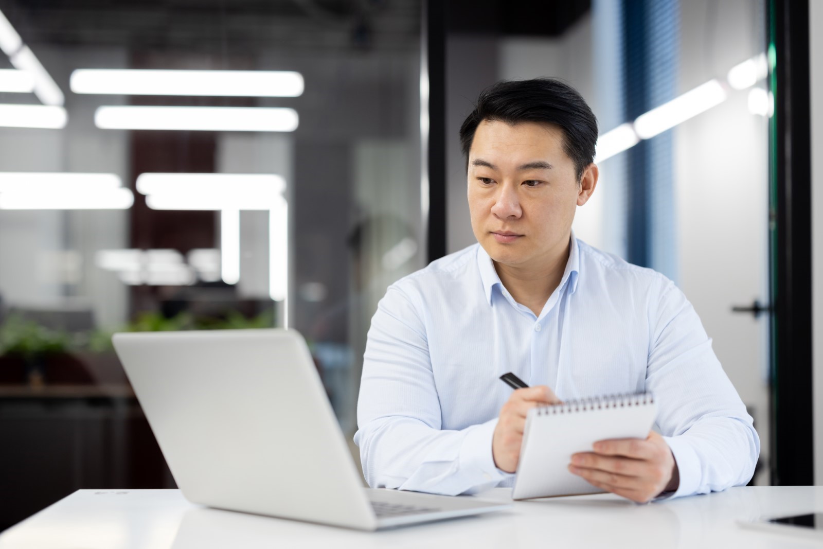 Office worker learning new things on his laptop while taking notes 