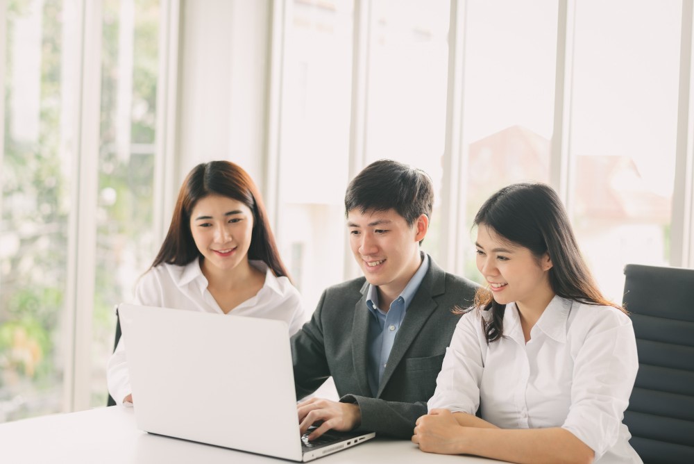 Team of three employees working on a laptop together on EOR service in Vietnam