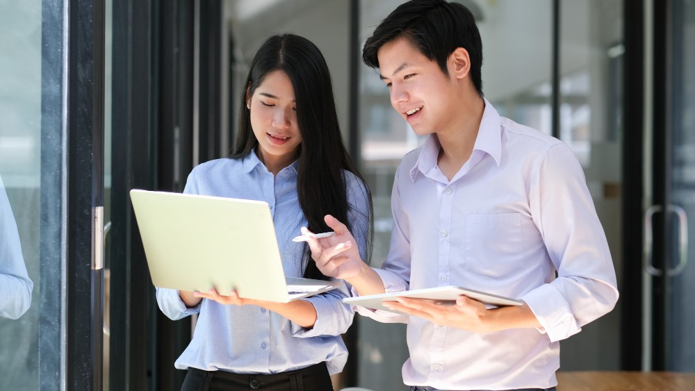 Two professionals discussing business insights on a laptop about EOR service in Vietnam